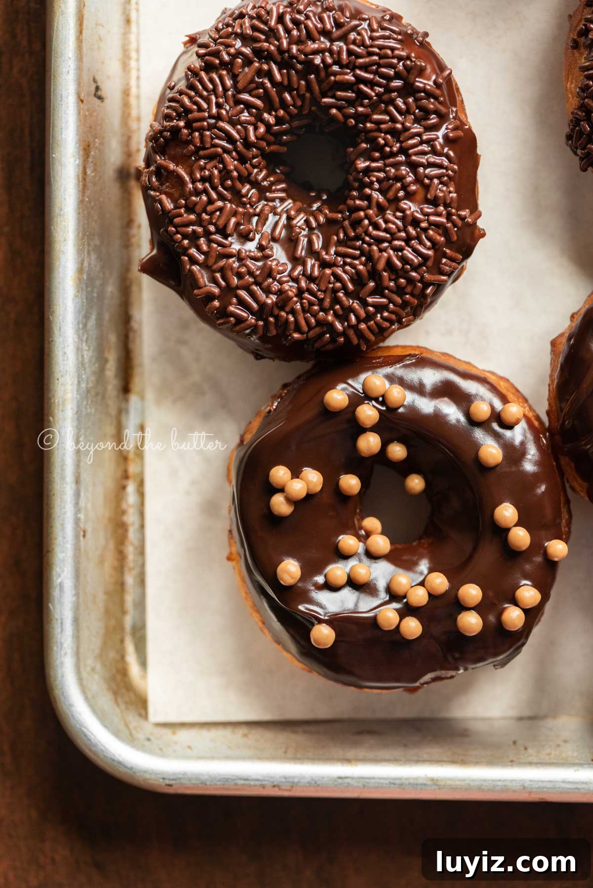 Homemade Donuts from Scratch: Classic Recipe for Soft, Fluffy Donuts 4 Chocolate glazed decorated donuts on a parchment paper lined baking sheet | All Images © Beyond the Butter™