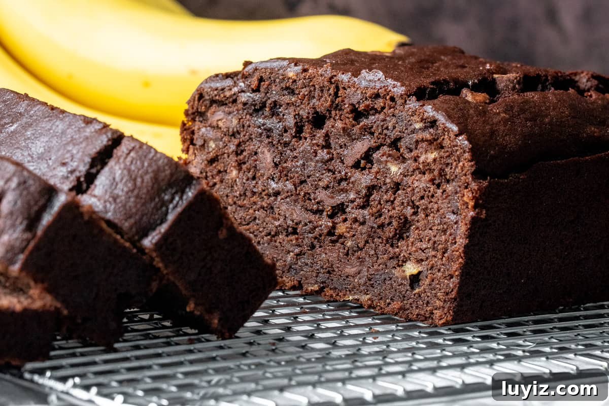 Chocolate banana bread cut in half with bunch of bananas