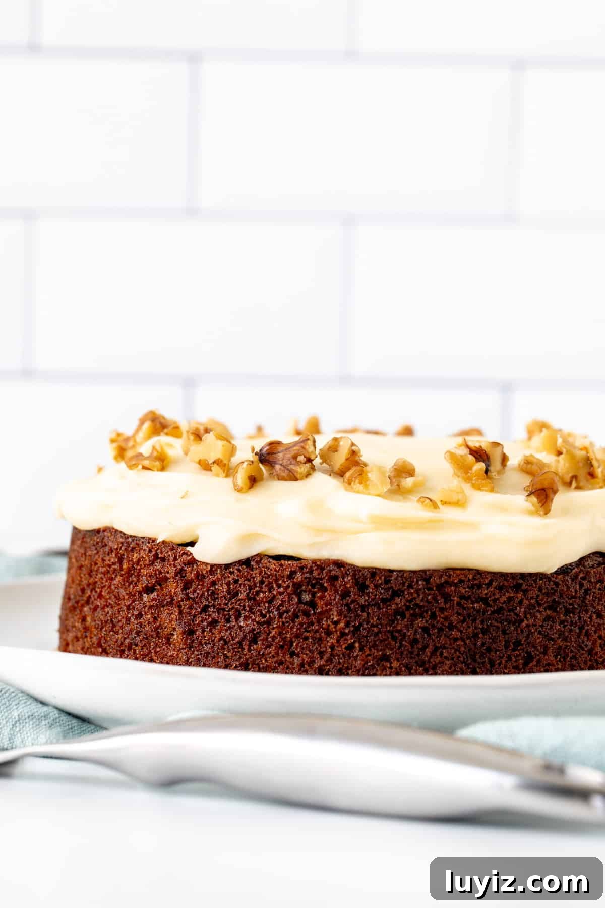Mini Carrot Cake Recipe: Moist Layered Cupcakes for Any Occasion 2 6-inch round carrot cake on a plate, topped with cream cheese frosting and walnuts