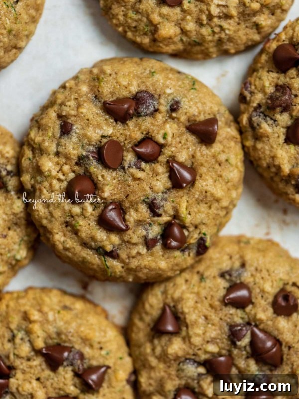 Carrot Cake Cookie Recipe: Moist, Spiced Cookies with Cream Cheese Frosting 15 Zucchini chocolate chip oatmeal cookies on a parchment paper lined baking sheet.