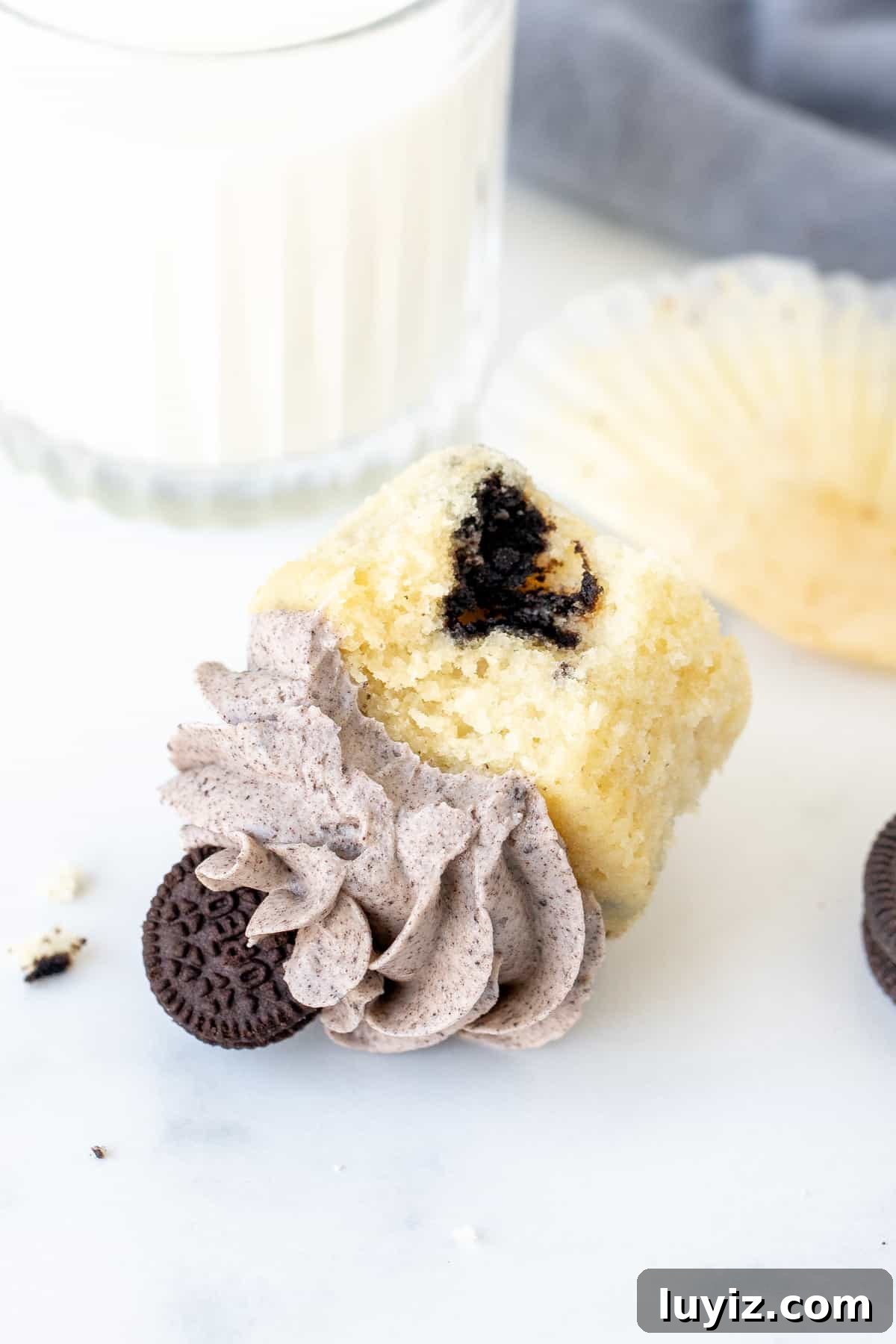 Decadent Oreo Cupcakes Recipe with Creamy Filling 7 Oreo cupcake with a bite taken out, on its side with glass of milk