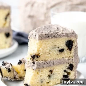Slice of Oreo cake with a bite taken out of it, with a glass of milk