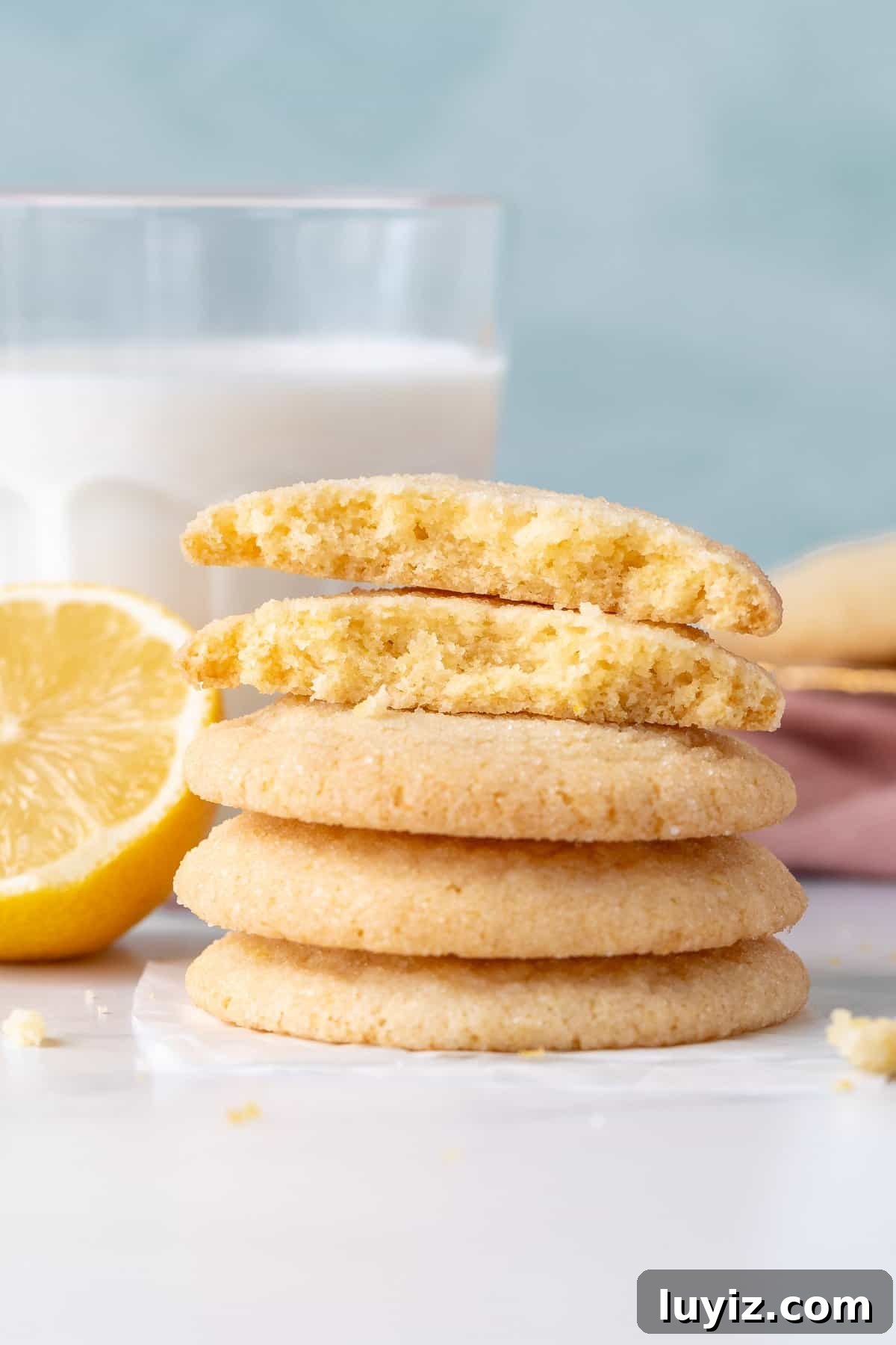 Crisp Lemon Sugar Cookies with Zesty Glaze Recipe 8 Lemon sugar cookies stacked on top of each other, with top cookie broken in half
