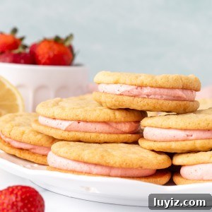 Plate of lemon sandwich cookies with strawberry frosting, with cookies on top of each other