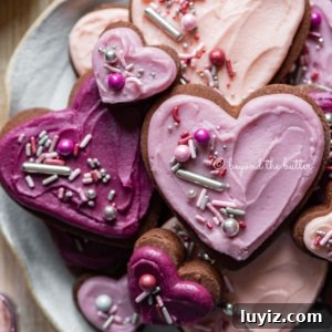 Chocolate Cut-Out Cookies: Classic Cocoa Sugar Cookie Recipe 11 Plate full of heart-shaped chocolate cut out sugar cookies decorated with buttercream frosting and sprinkles.