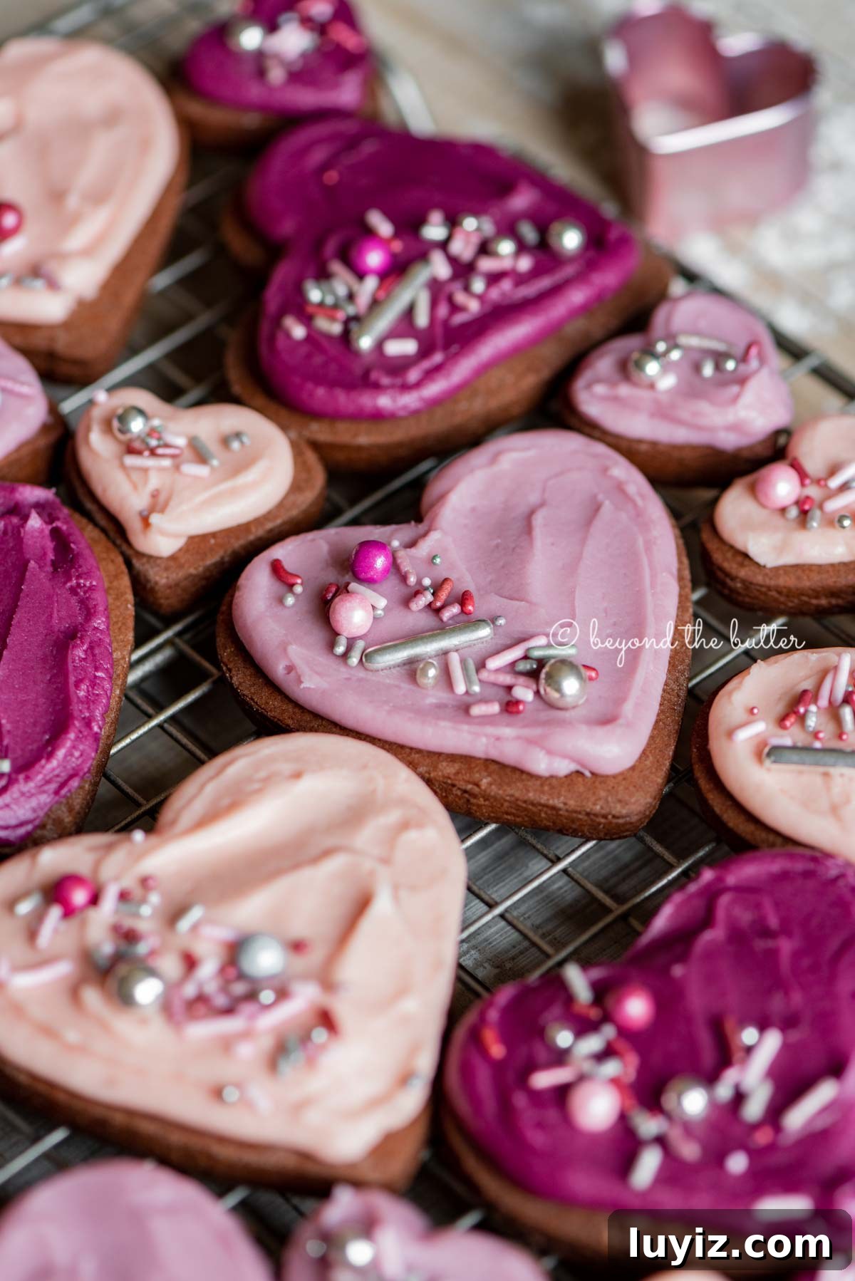 Chocolate Cut-Out Cookies: Classic Cocoa Sugar Cookie Recipe 3 Angled image of decorated chocolate cut out sugar cookies on a wire cooling rack on light wood colored background | All Images © Beyond the Butter®