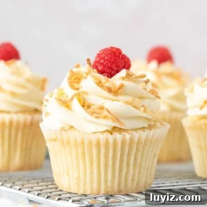 Coconut Cupcakes Recipe: Moist, Tropical Frosted Treats 7 Coconut cupcakes with coconut frosting, decorated with toasted coconut on a cooling rack