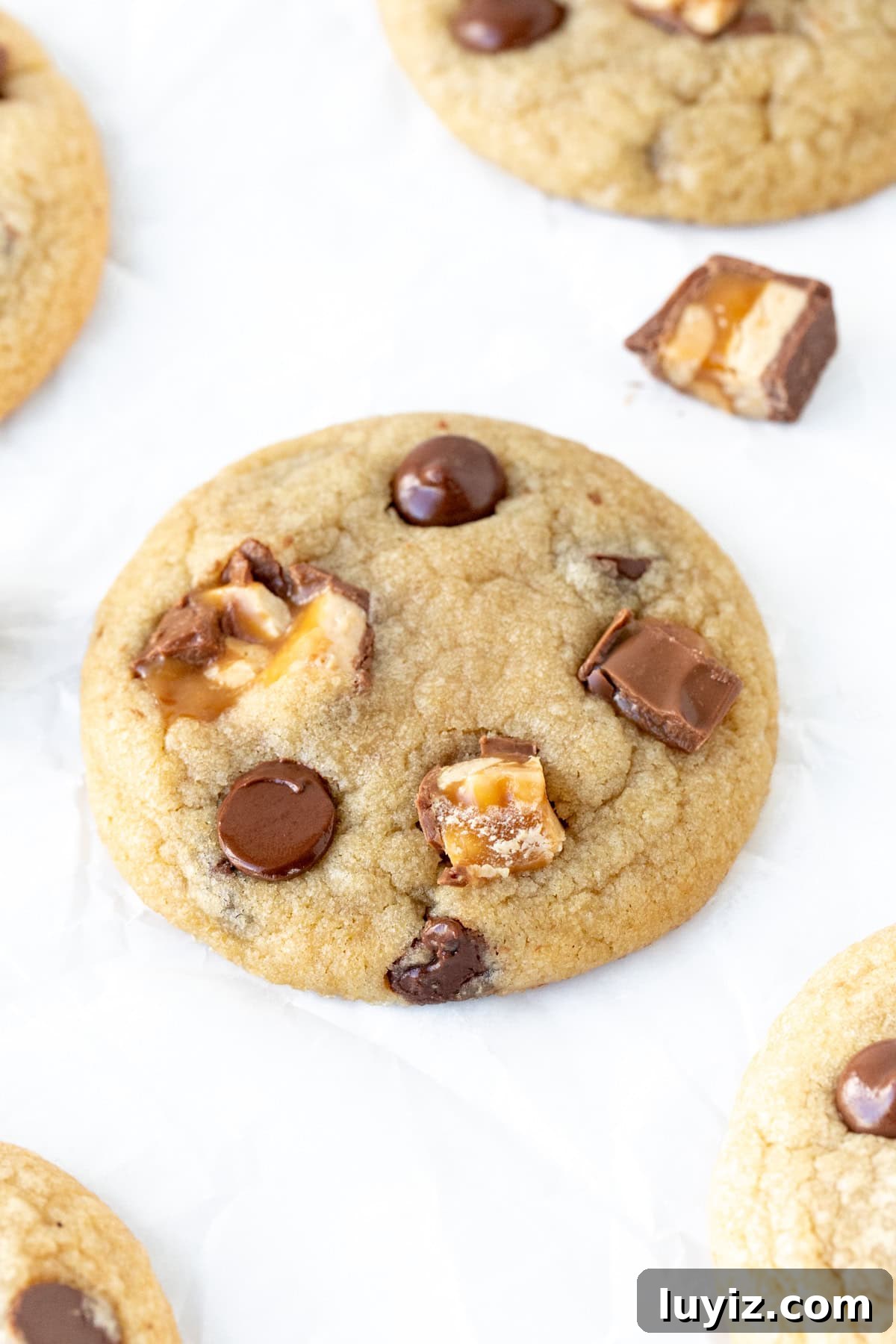 Snickers Stuffed Chocolate Chip Cookies: Gooey Caramel & Peanuts 7 Snickers chocolate chip cookie on parchment paper