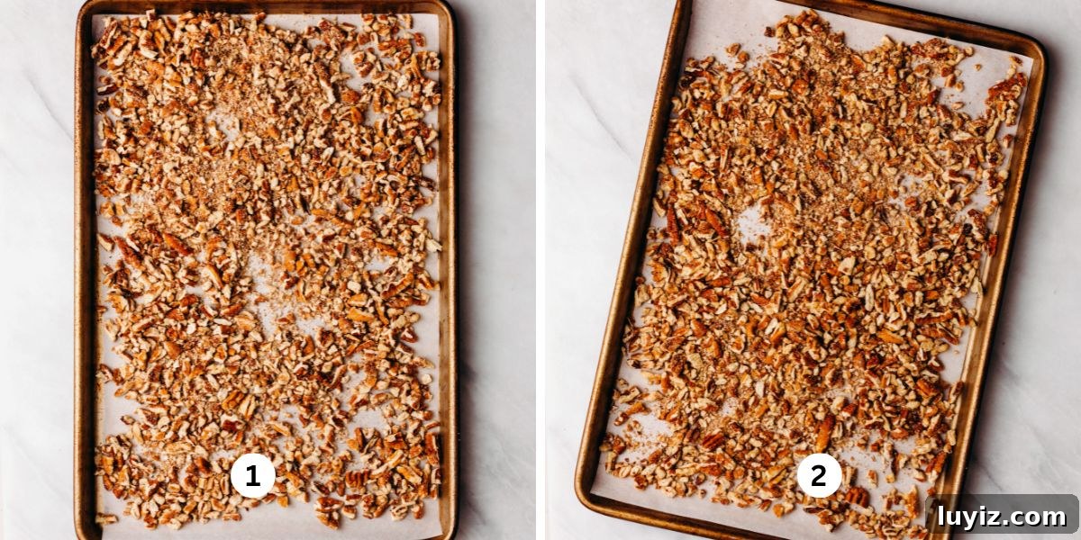 Pecan Pie Cheesecake Recipe — Decadent Homemade Dessert 11 Toasting chopped pecans on a parchment paper lined baking sheet on a white background.
