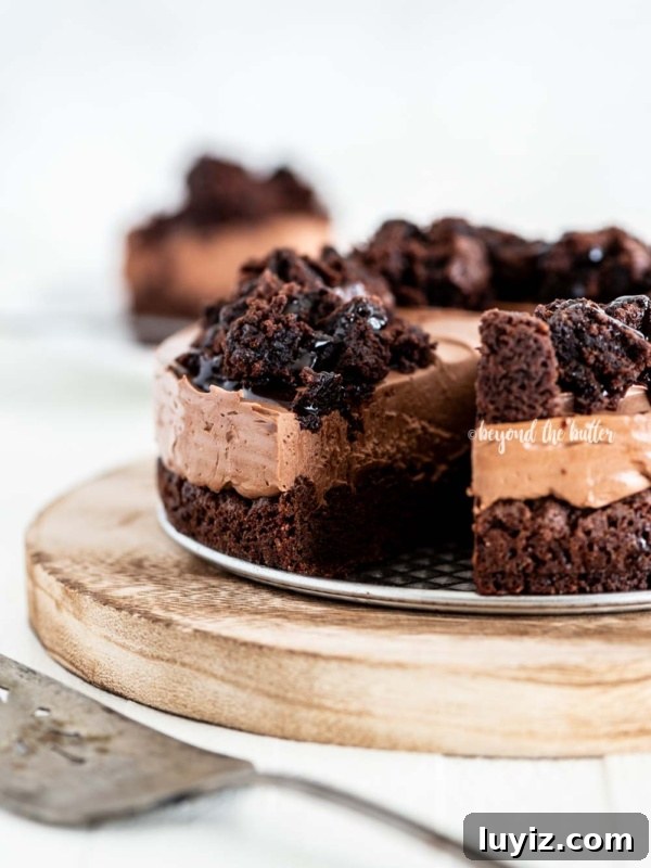 Pecan Pie Cheesecake Recipe — Decadent Homemade Dessert 19 Chocolate brownie cheesecake with slice cut on wood cake plate and cake server in foreground and slice of cake in background on white wood table.