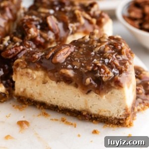 Pecan Pie Cheesecake Recipe — Decadent Homemade Dessert 20 Sliced pecan pie cheesecake sprinkled with sea salt flakes on a white marble cake stand placed next to a small bowl of pecans on a white background.