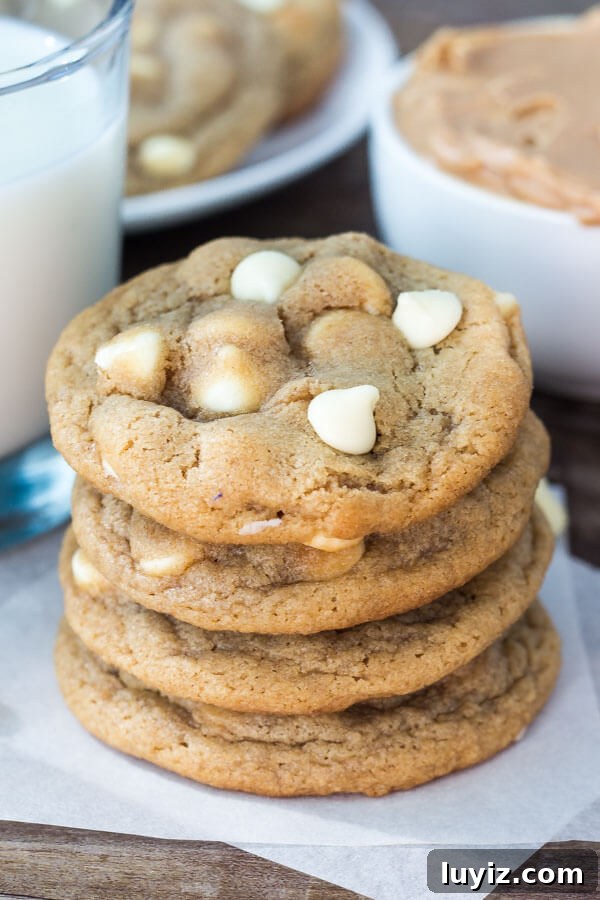 Peanut Butter White Chocolate Chip Cookies Recipe for Chewy Cookies 5 Stack of peanut butter white chocolate chip cookies. Glass of milk and second plate of cookies in the background.