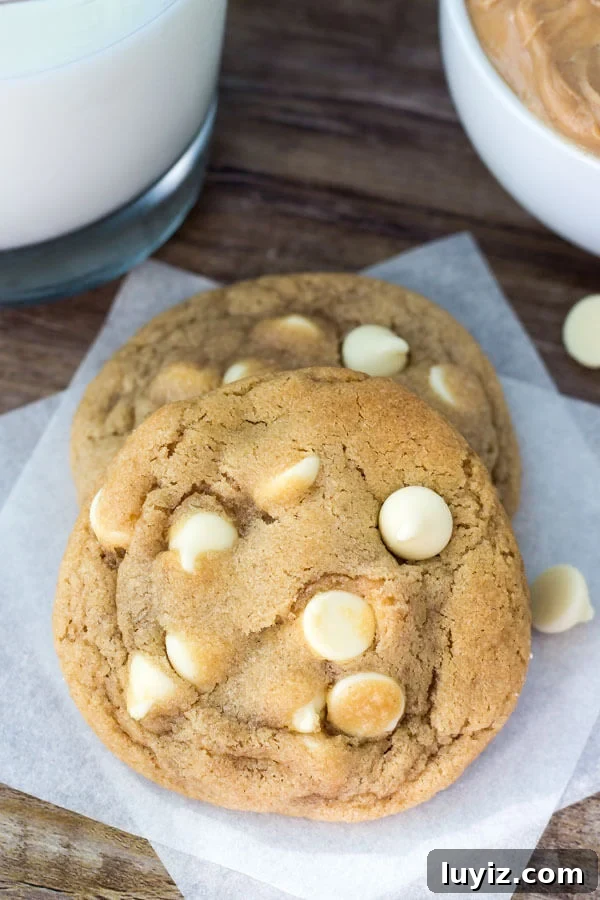 Peanut Butter White Chocolate Chip Cookies Recipe for Chewy Cookies 6 Two peanut butter white chocolate chip cookies on white napkin with white chocolate chips scattered around.