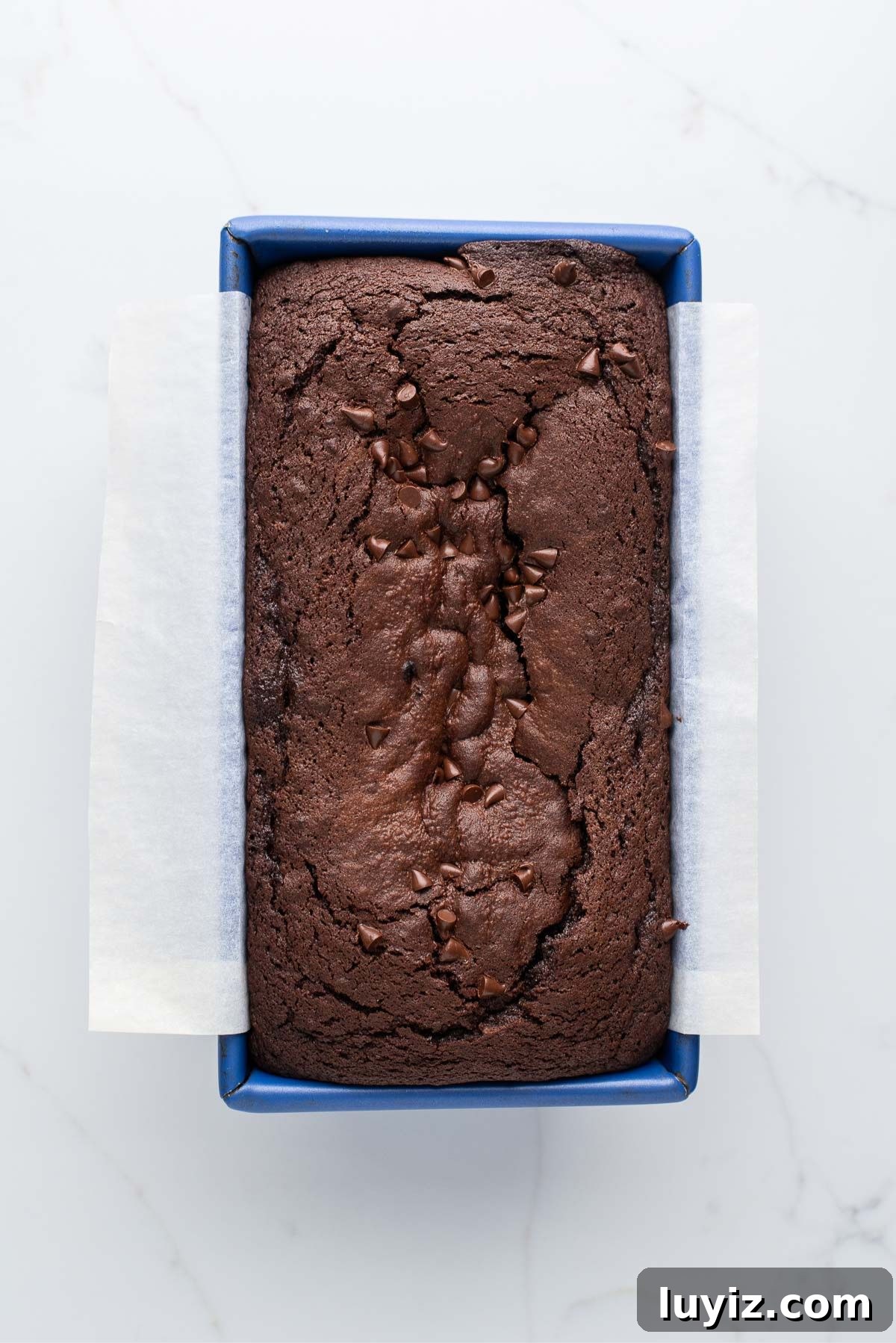 Decadent Brownie Loaf Recipe: Fudgy Chocolate Bread Tutorial 10 Baked brownie bread in a blue metal loaf tin on a white marbled background.