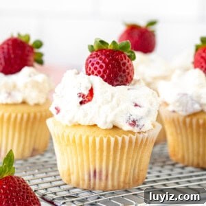 Strawberry Cream Cupcakes Recipe: Light, Fresh & Frosted 5 Strawberries and cream cupcakes topped with a strawberry on a cooling rack