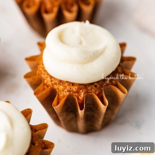 15 Delightful Easter Desserts to Impress Your Guests 11 Super moist carrot cake cupcakes topped with cream cheese frosting on a white background.