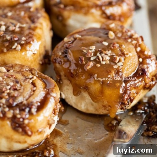 15 Delightful Easter Desserts to Impress Your Guests 13 Sticky buns placed on a stainless steel baking sheet with a small knife placed next to them on a white background.