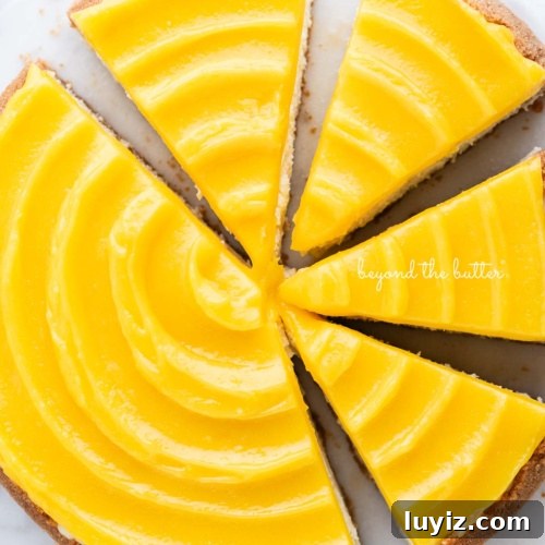 15 Delightful Easter Desserts to Impress Your Guests 7 Lemon cheesecake topped with lemon curd cut into slices on a marble cake plate with white background.