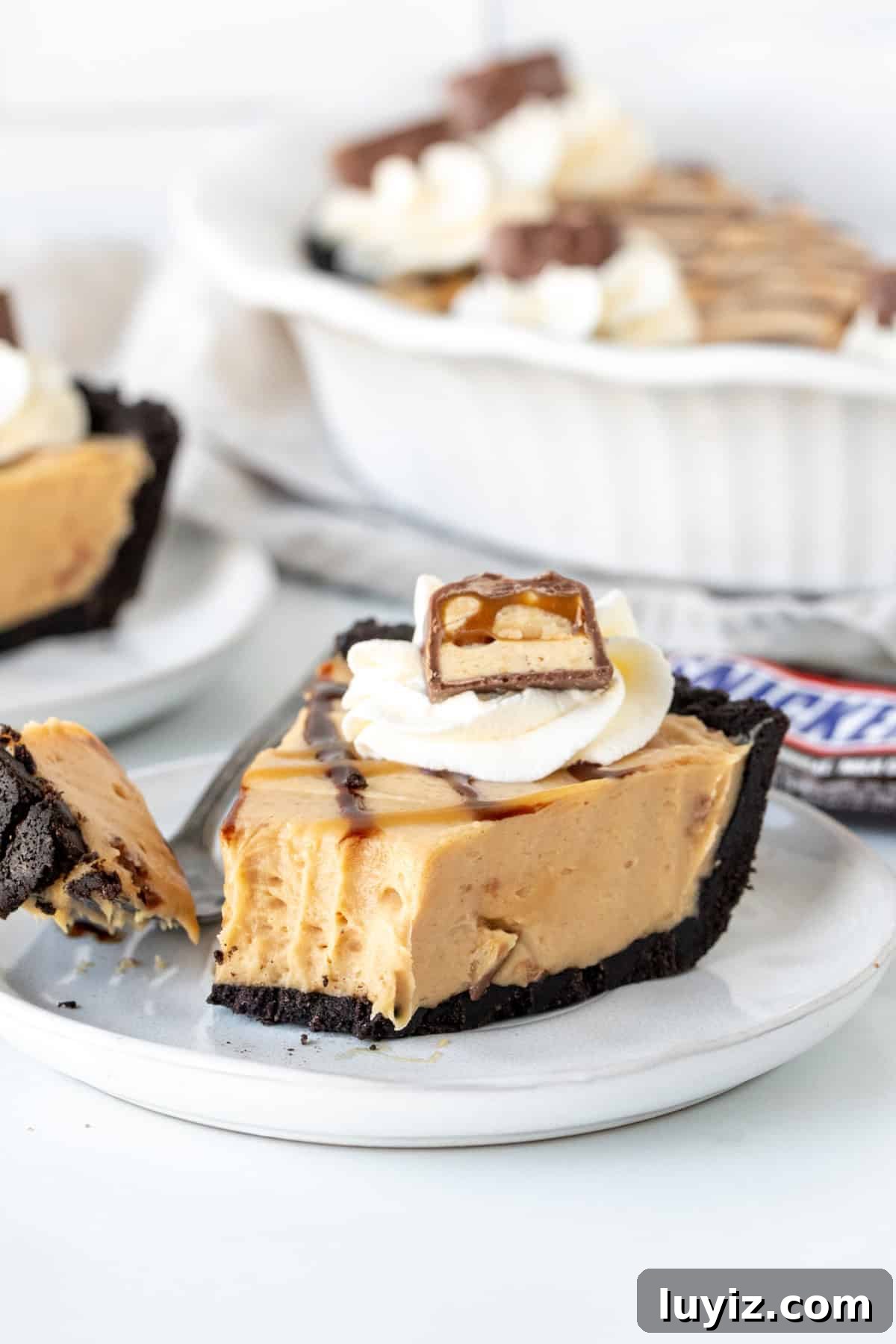 Decadent Snickers Pie Recipe — Chocolate Caramel Peanut Tart 3 Slice of Snickers pie with a bite taken out