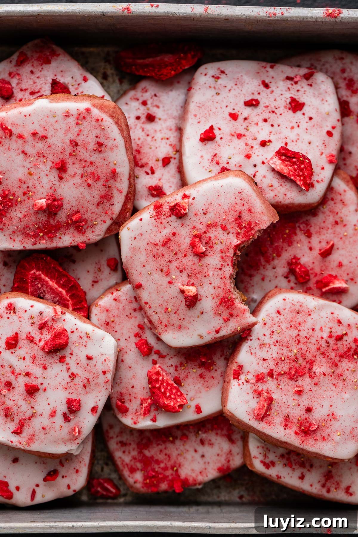 Strawberry Shortbread Cookie Recipe for Tender, Buttery Cookies 11 Strawberry shortbread cookies topped with a powdered sugar glaze and freeze dried strawberry bits randomly placed in a vintage baking tin.