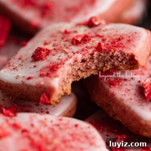 Strawberry Shortbread Cookie Recipe for Tender, Buttery Cookies 12 Strawberry shortbread cookies topped with glaze and freeze-dried strawberry bits randomly placed in a vintage baking tin.