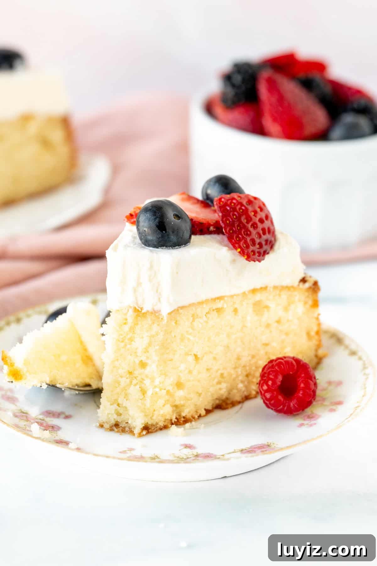 Decadent Berries and Cream Layer Cake Recipe 9 Slice of berries and cream cake with a bite taken out.