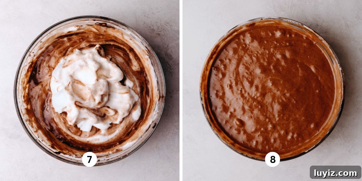 Light and Airy Chocolate Chiffon Cake Recipe 8 Folding meringue into chocolate chiffon cake batter in a large glass bowl on a white marbled background.