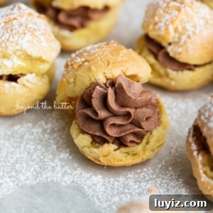 How to Make Classic Cream Puffs: Puff Pastry Filled with Vanilla Cream 17 Cream puffs filled with chocolate whipped cream and dusted with powdered sugar on a parchment paper lined baking sheet.