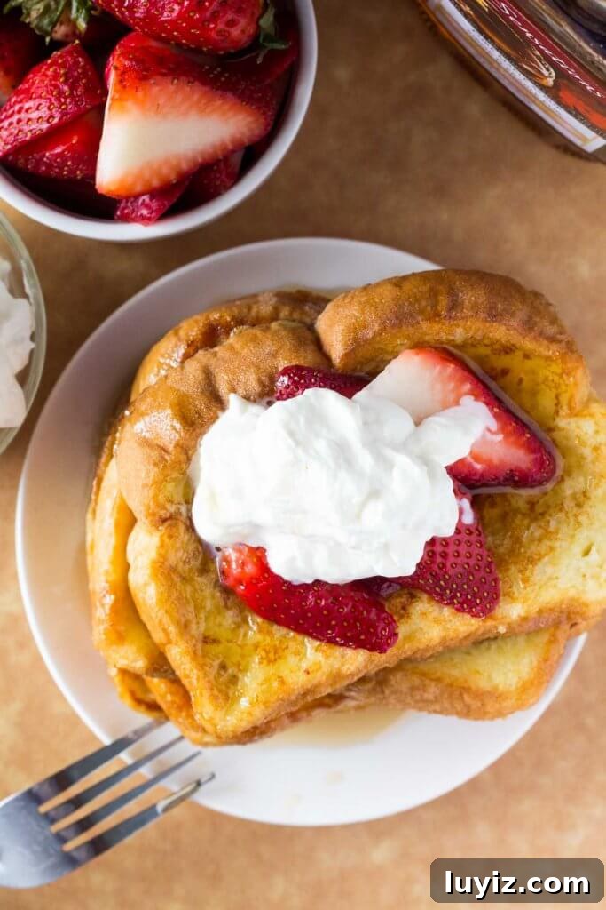 Classic French Toast Recipe: Crispy Golden Brunch Favorite 4 Overhead shot of a stack of french toast with a bowl of strawberries and bottle of maple syrup.