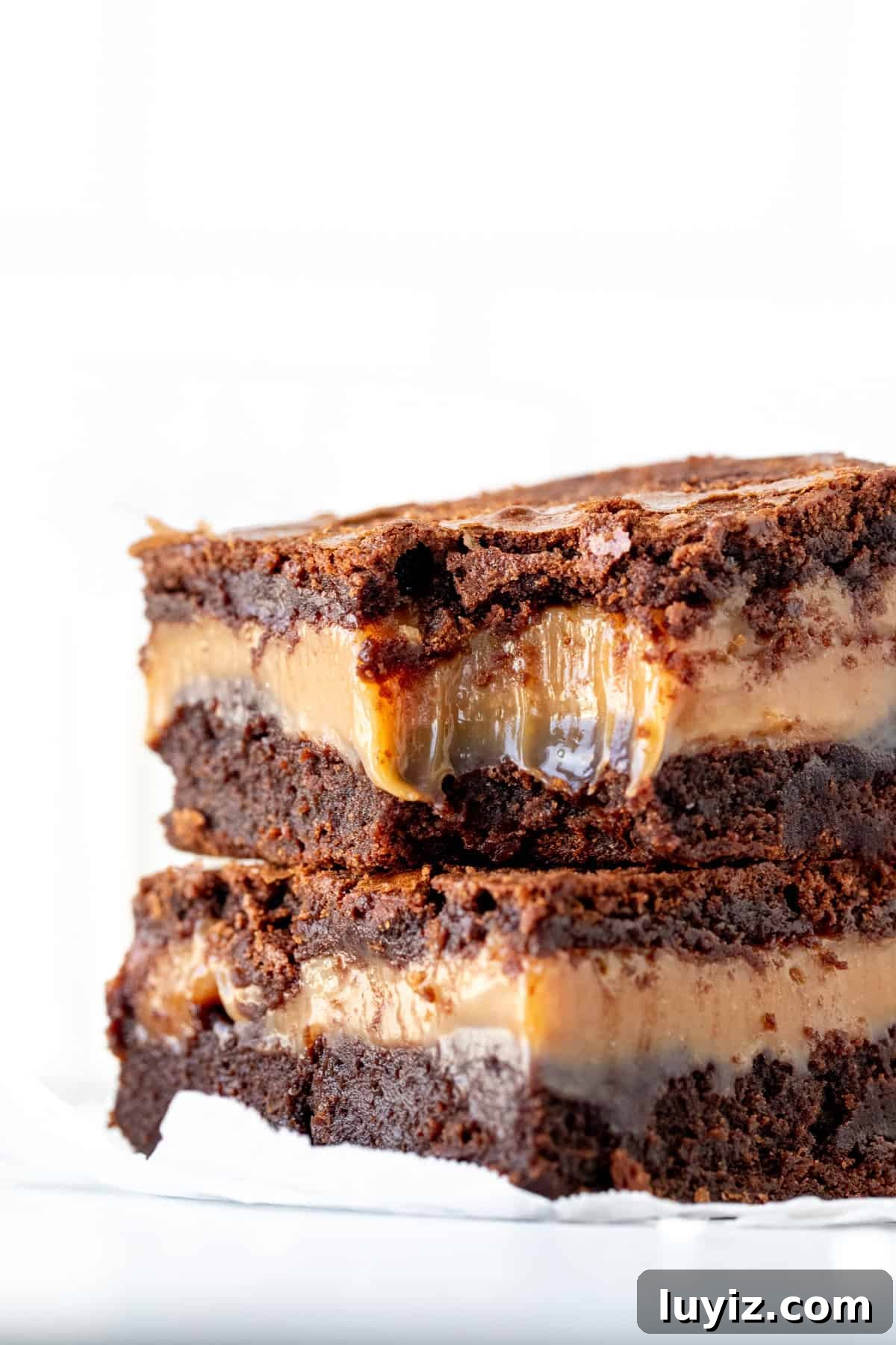 Salted Caramel Brownies with Gooey Chocolate Swirls 8 2 caramel stuffed brownies on top of each other, with a bite taken out of the top brownie