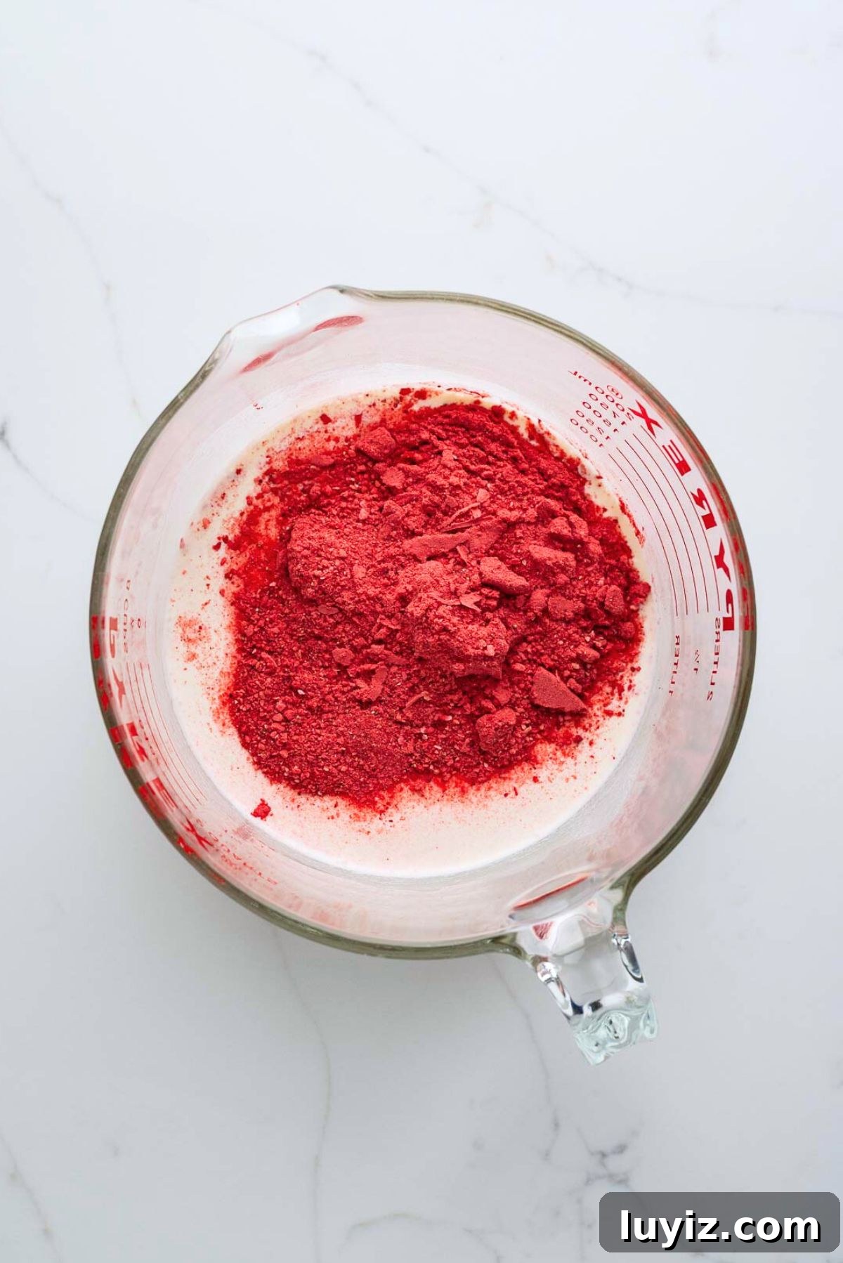 Creamy Homemade Strawberry Ice Cream Recipe You’ll Love 6 Strawberry ice cream ingredients added to a large glass mixing bowl on a white marbled background.