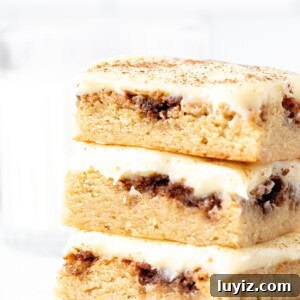 Cinnamon Roll Blondies Recipe — Gooey Swirl Dessert Bars 8 Stack of three cinnamon roll blondies with cream cheese icing, one on top of each other