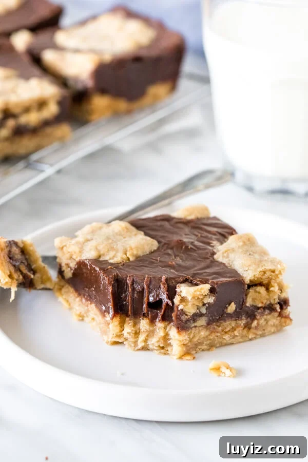 Chewy Oatmeal Fudge Bars with Chocolate Swirls 4 Slice of oatmeal fudge bar with a bite taken out of it on a plate with glass of milk.