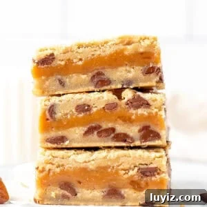Salted Caramel Chocolate Chip Cookie Bars: Gooey & Chewy Recipe 9 Stack of three caramel chocolate chip bars with glass of milk