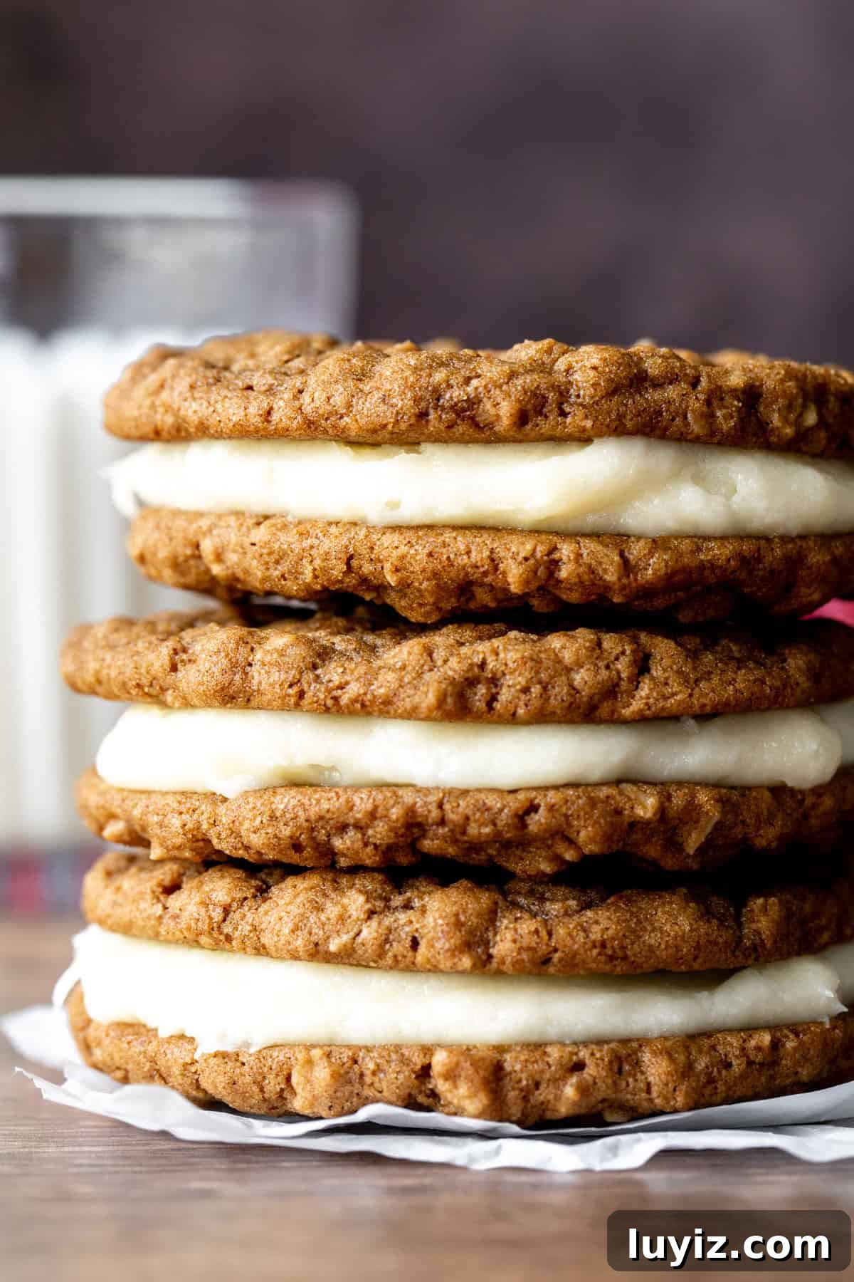 Gingerbread Oatmeal Cream Pies Recipe — Soft Spiced Sandwich Cookies 3 Gingerbread oatmeal cream pie cookies, stacked on top of each other with glass of milk