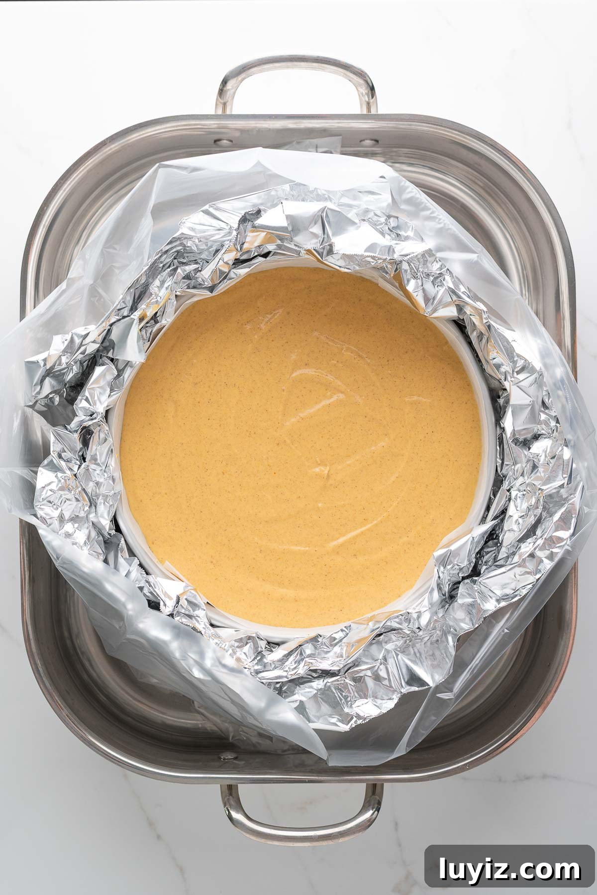 Creamy Pumpkin Cheesecake Recipe for Fall Desserts 16 Baking a pumpkin cheesecake in a roasting pan water bath filled with hot water.