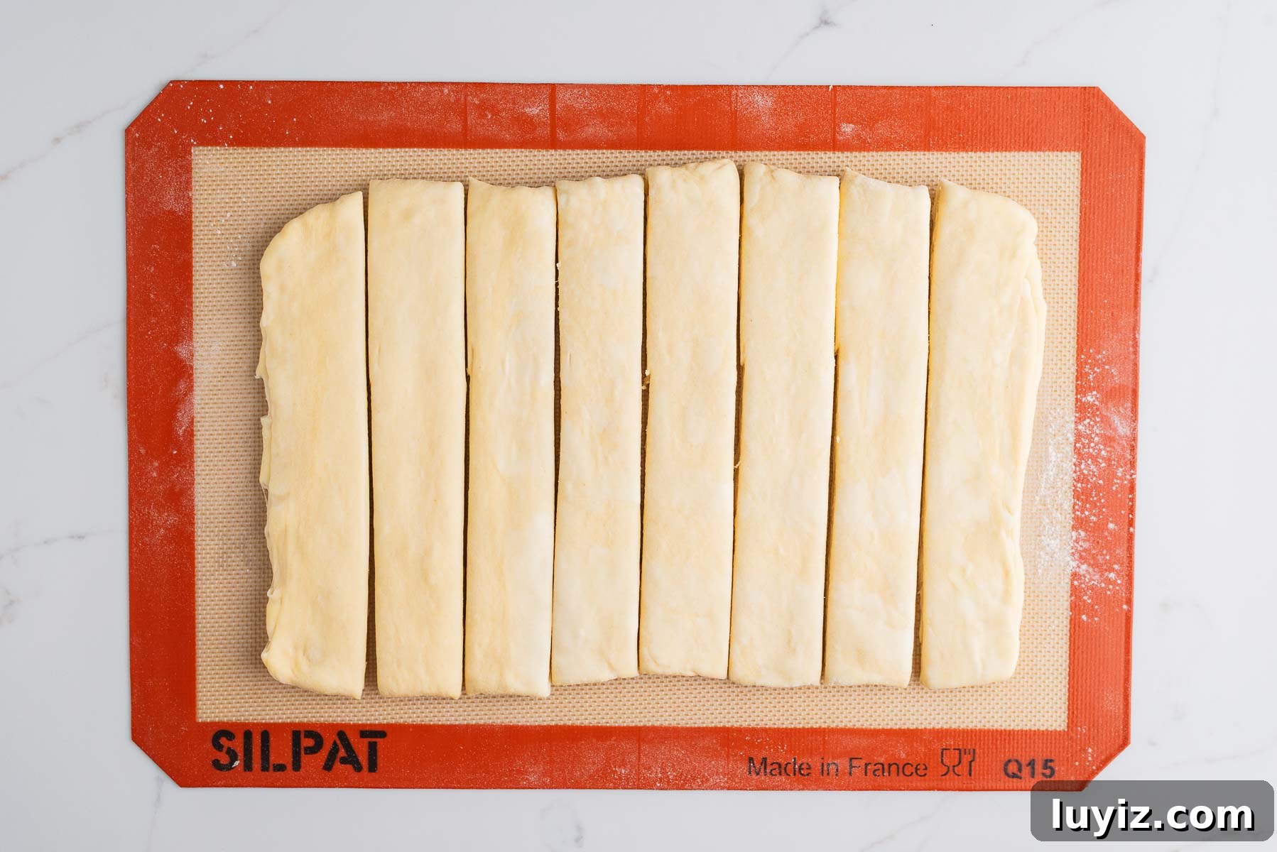Chocolate Croissant Loaf Recipe: Flaky Chocolate Swirl Bread 13 Rolled out laminated croissant loaf dough and cut into eight equally sized strips on a silicone baking sheet.