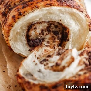 Chocolate Croissant Loaf Recipe: Flaky Chocolate Swirl Bread 24 Chocolate croissant loaf pulled apart to see the inside chocolatey, flaky layers on brown parchment paper.