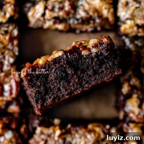 Salted pecan pie brownies placed on brown parchment paper with the center brownie placed on its side on an angle.