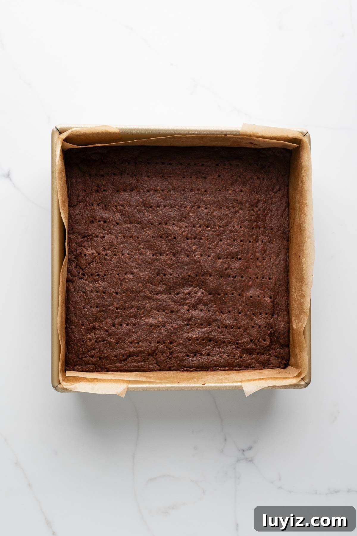 Classic Chocolate Shortbread Cookies Recipe for Homemade Treats 12 Baked chocolate shortbread biscuits in a parchment paper lined metal baking tin on a white marbled surface.