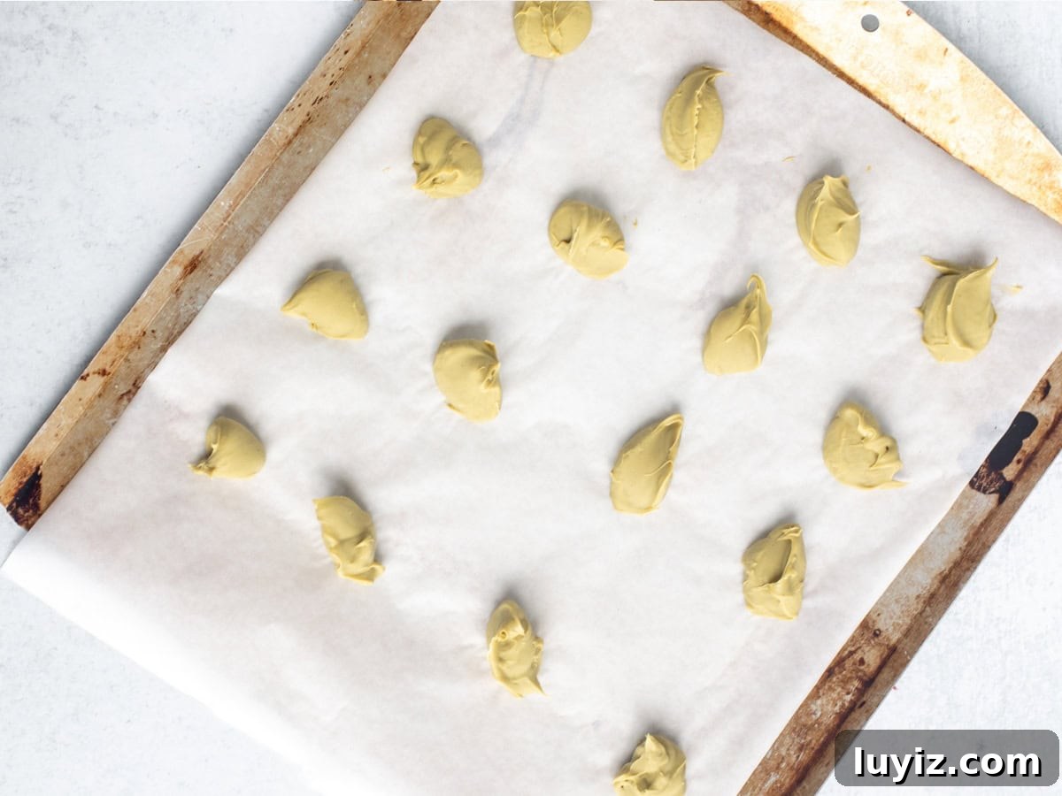 Crispy Pistachio Chocolate Chip Cookies Recipe 4 Lined cookie sheet with spoonfuls of pistachio spread