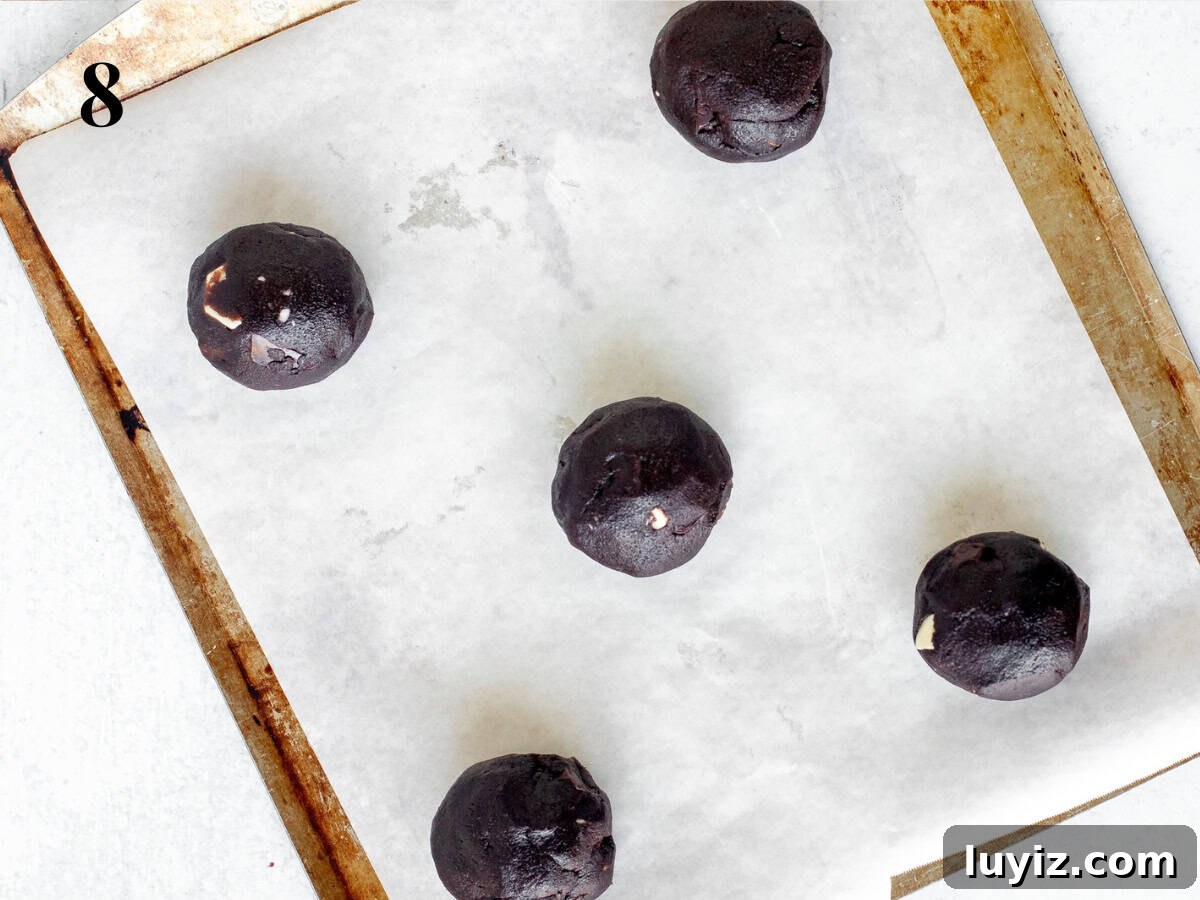 Ultimate Triple Chocolate Chip Cookies Recipe for Chocolate Lovers 6 large chocolate cookie dough balls on lined cookie sheet