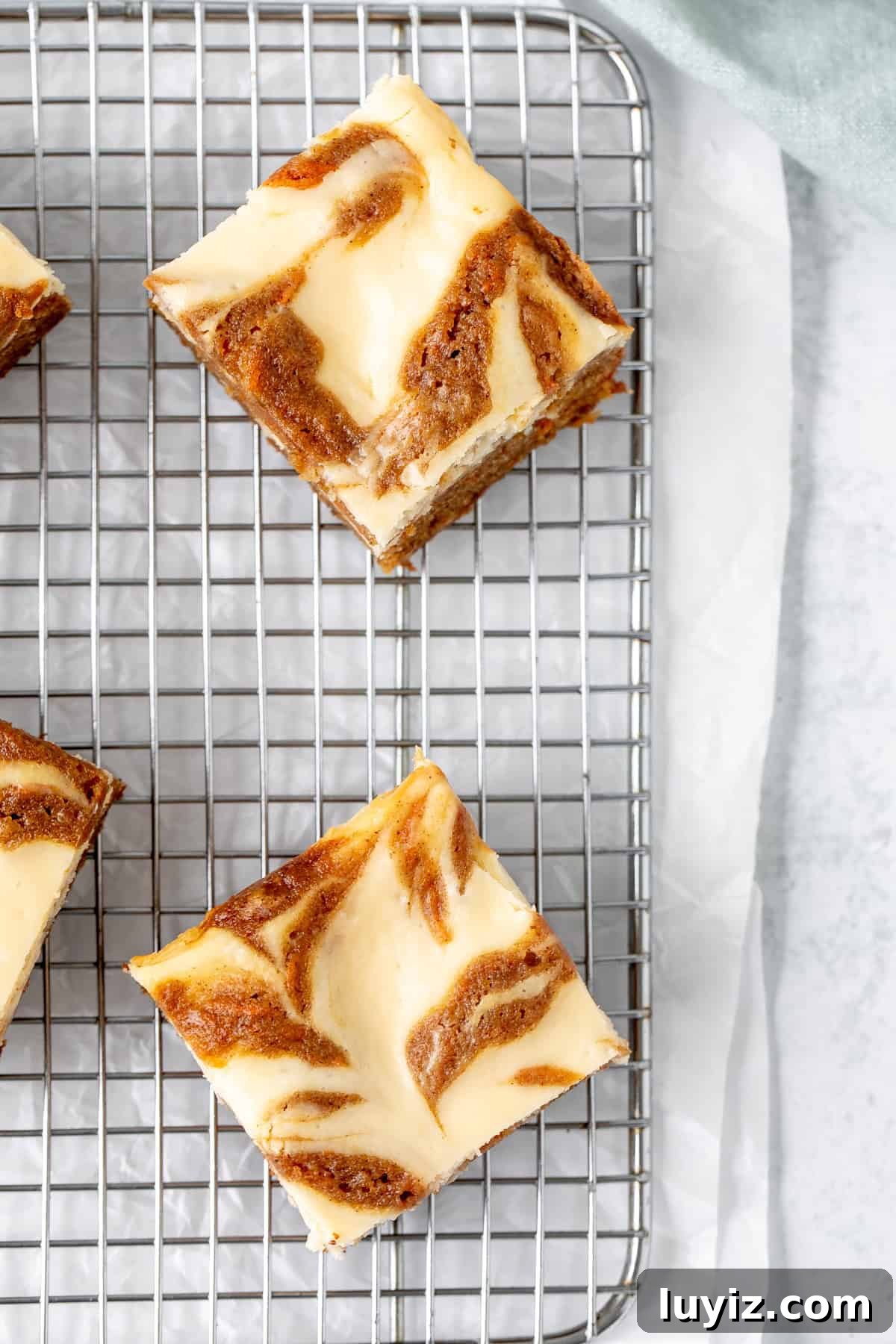 Carrot Cake Cheesecake Bars Recipe — Moist Spiced Dessert Bars 8 Carrot cake bars swirled with cheesecake on a cutting board