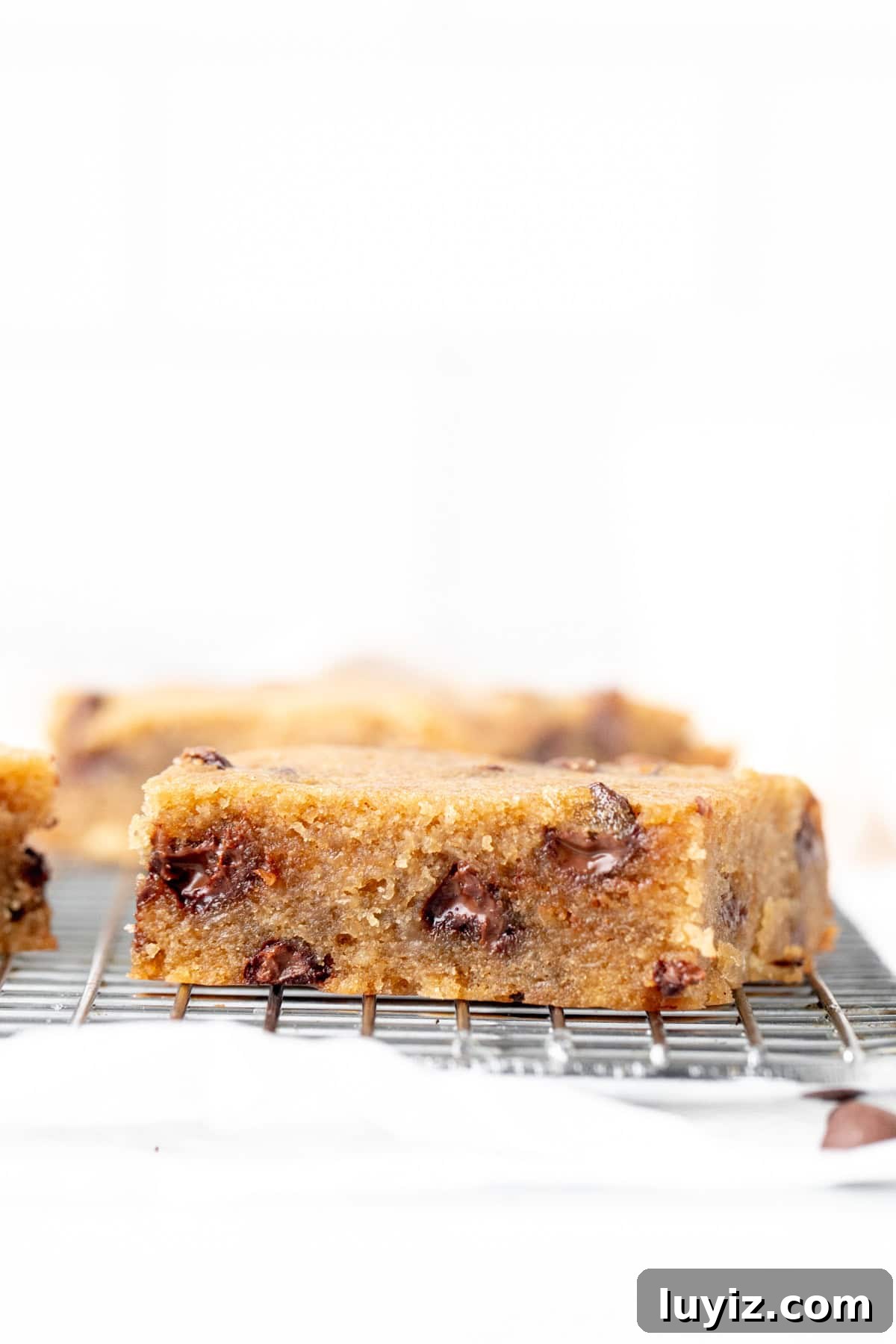 Banana Chocolate Chip Dessert Bars — Moist Baked Banana Squares 3 chocolate chip banana bar on a cooling rack