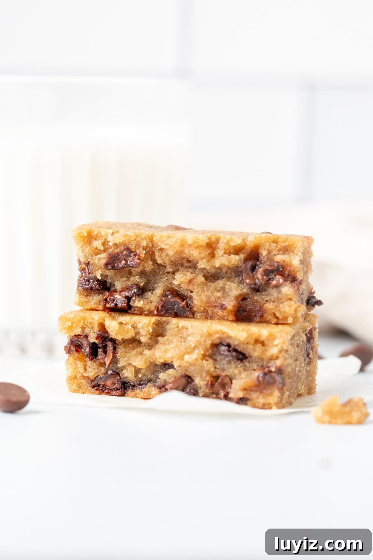 Banana Chocolate Chip Dessert Bars — Moist Baked Banana Squares 7 Banana chocolate chip bar broken in half with glass of milk