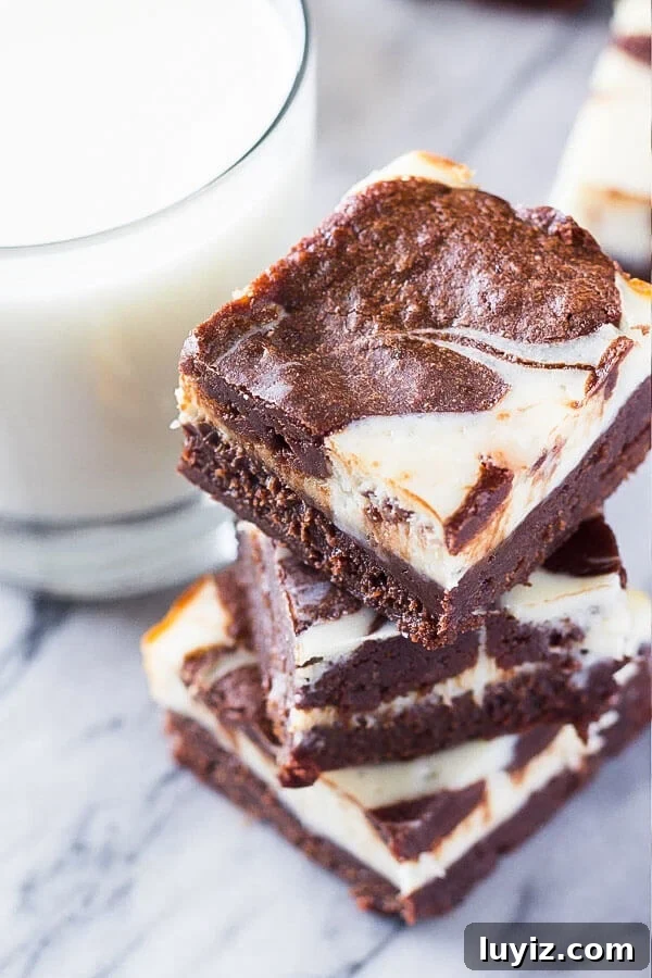Fudgy Cream Cheese Swirl Brownies: Rich Chocolate Cheesecake Bars 3 A stack of 3 cream cheese brownies with a glass of milk.