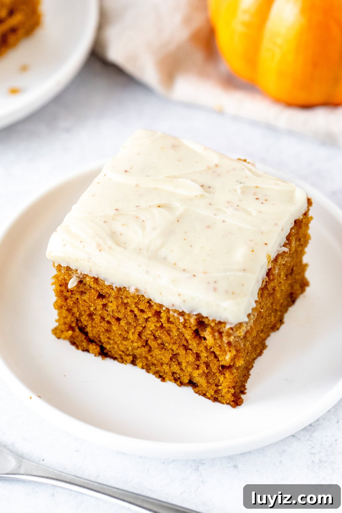 Ultimate Moist Pumpkin Cake Recipe for Fall Baking 4 slice of pumpkin sheet cake topped with brown butter cream cheese frosting