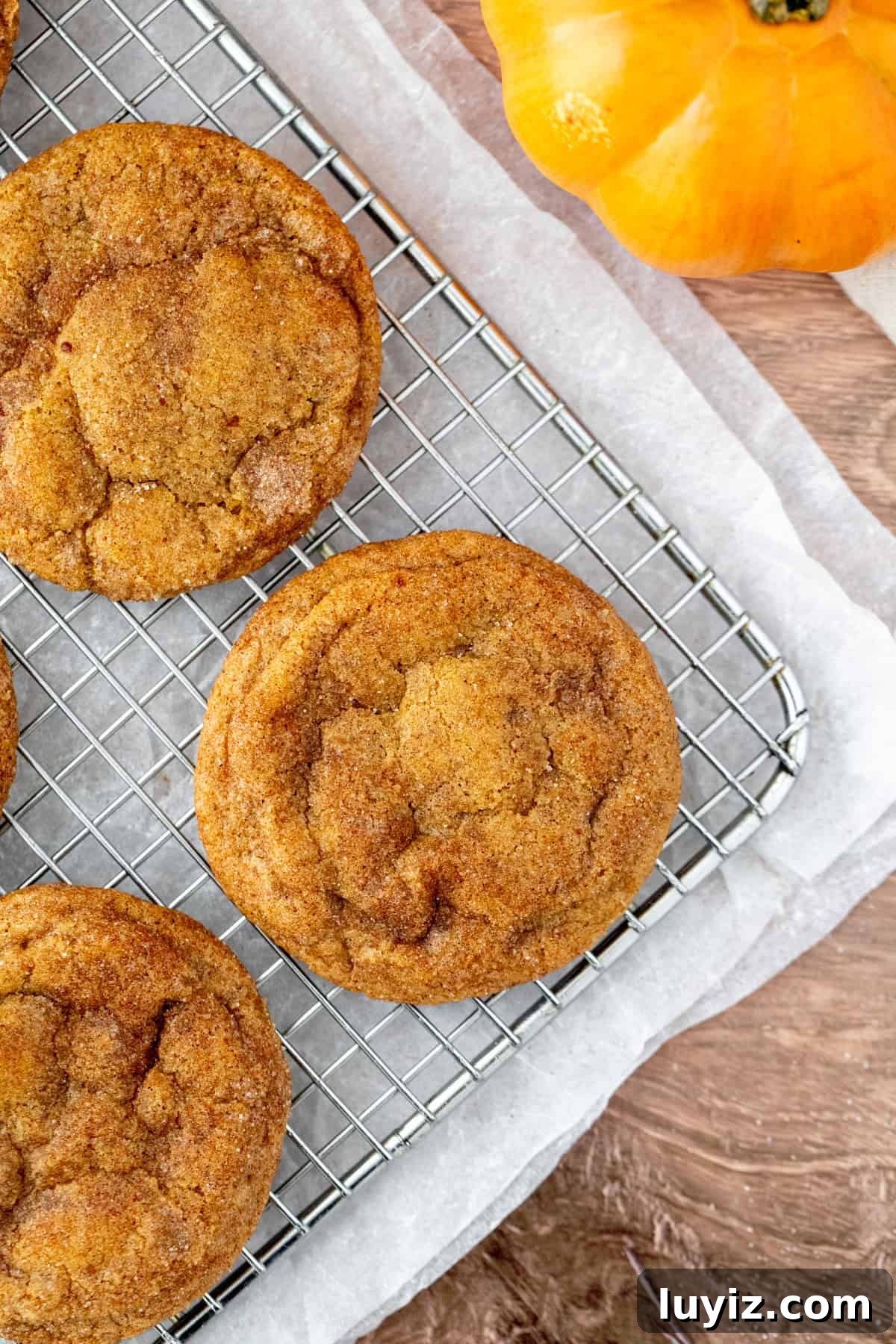 Pumpkin Cheesecake Cookie Recipe — Soft Pumpkin Cookies with Creamy Filling 7 Cheesecake stuffed pumpkin cookies on a cooling rack