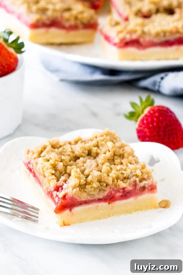 Homemade Strawberry Crumb Bars Recipe with Buttery Streusel 5 Strawberry bar with crumb topping on a white plate with a fork.