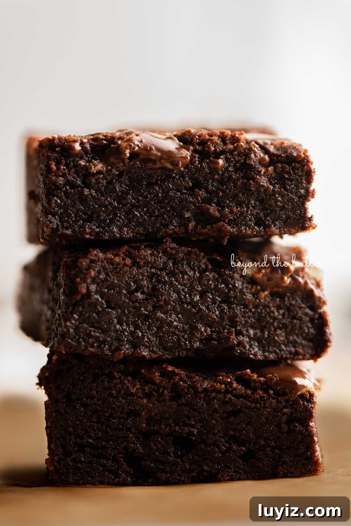 Decadent Double Chocolate Mint Brownies Recipe 3 Stacked mint chocolate brownies on brown parchment paper | © Beyond the Butter®